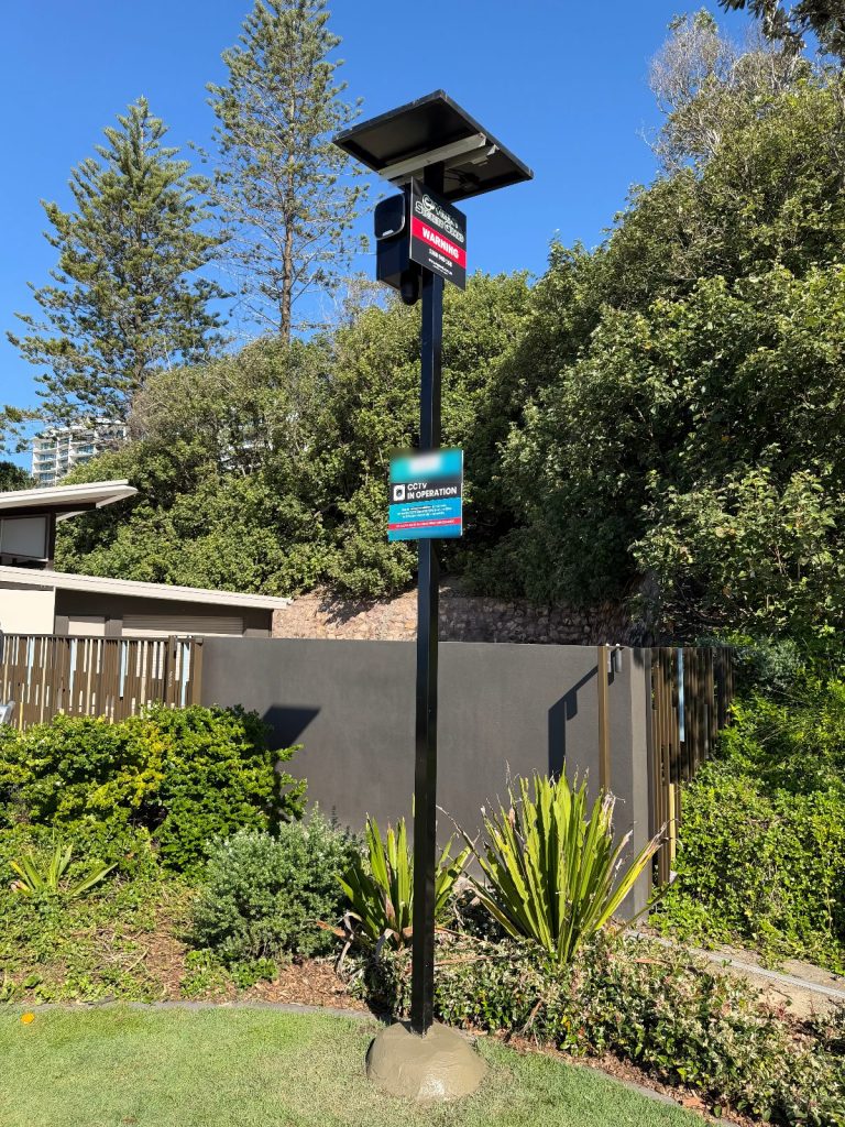 Colour-matched black solar CCTV pole on a rock-look temporary base in a landscaped public park
