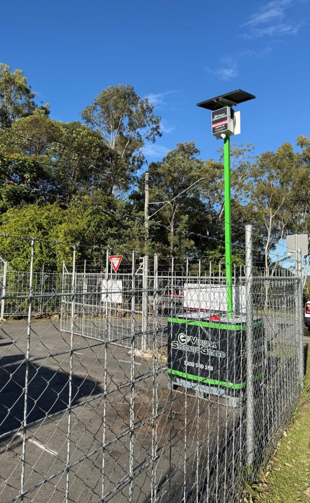 VSG green solar CCTV pole on a portable ballast base inside a fenced works depot